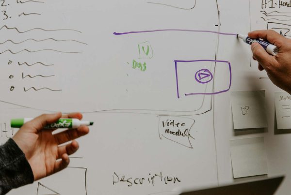 Two colleagues draw on a whiteboard as part of a meeting